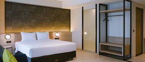 Una habitación de hotel moderna con una cama grande, lámparas de noche, una pequeña mesa redonda y un armario empotrado con estantes.