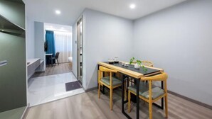 A modern dining area with a wooden table and chairs, a small plant, and a view into a room with a blue curtain.