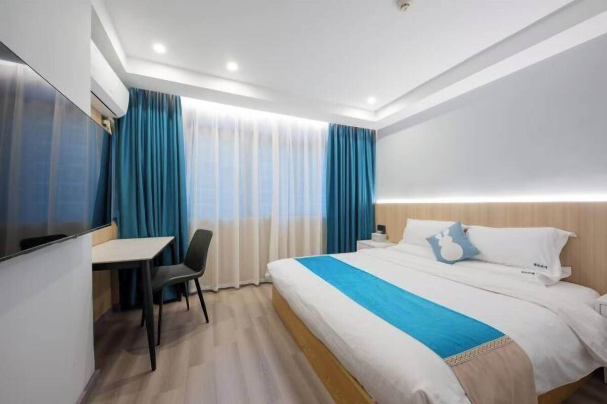 A hotel room with a bed, a desk, and a chair.