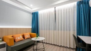 A modern hotel room with a sofa, a small round table, and a dining table.