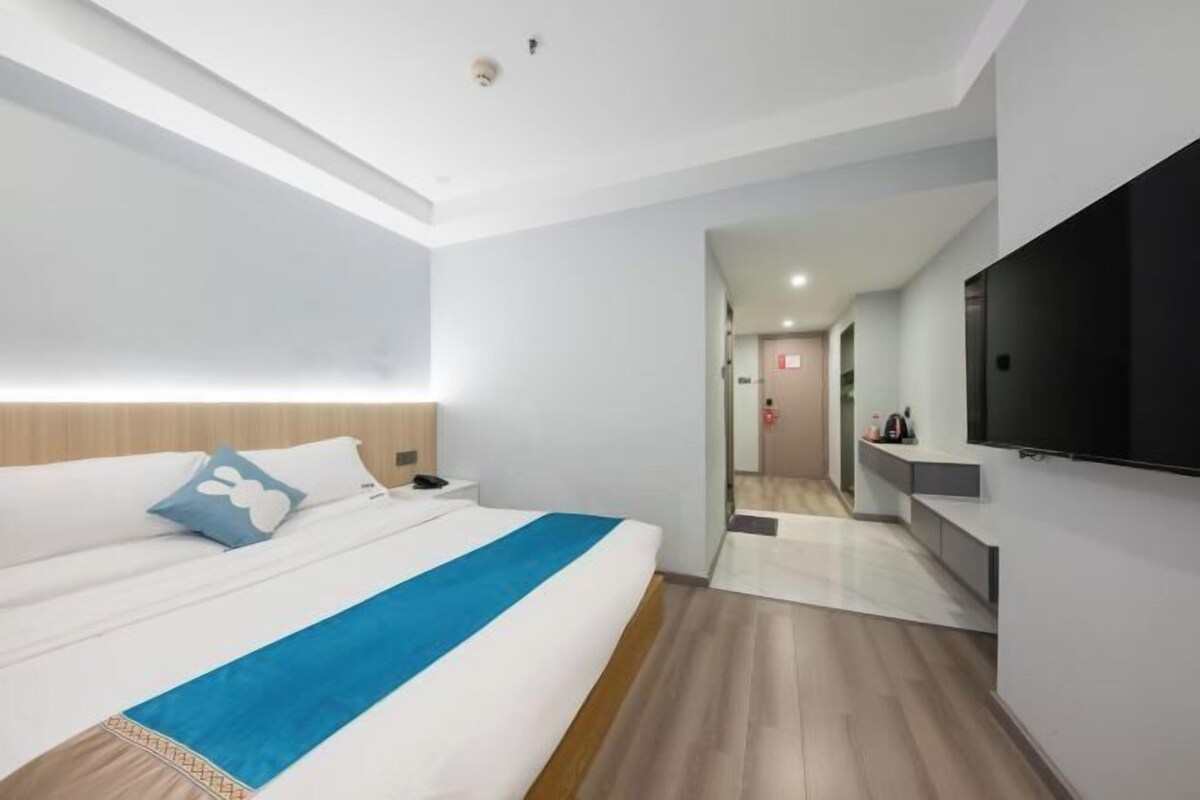 A modern hotel room with a large bed, a flat-screen TV, and a walk-in closet.