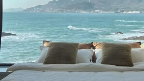 A bed with pillows and a view of the ocean and mountains. - Piaoyang Guohai Guesthouse (Zhoushan)