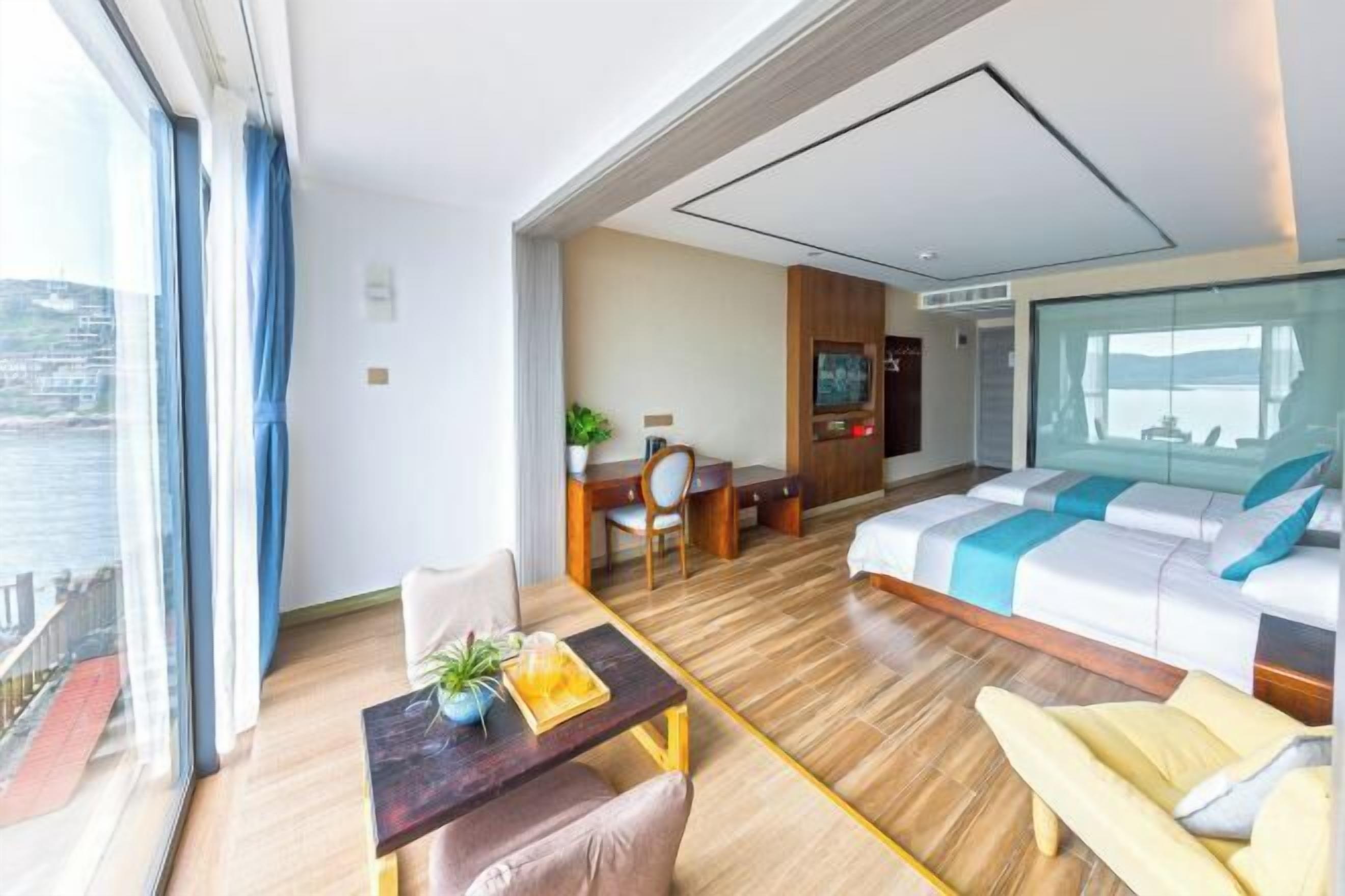 A modern hotel room with a balcony, a dining area, a sofa, and a bed.