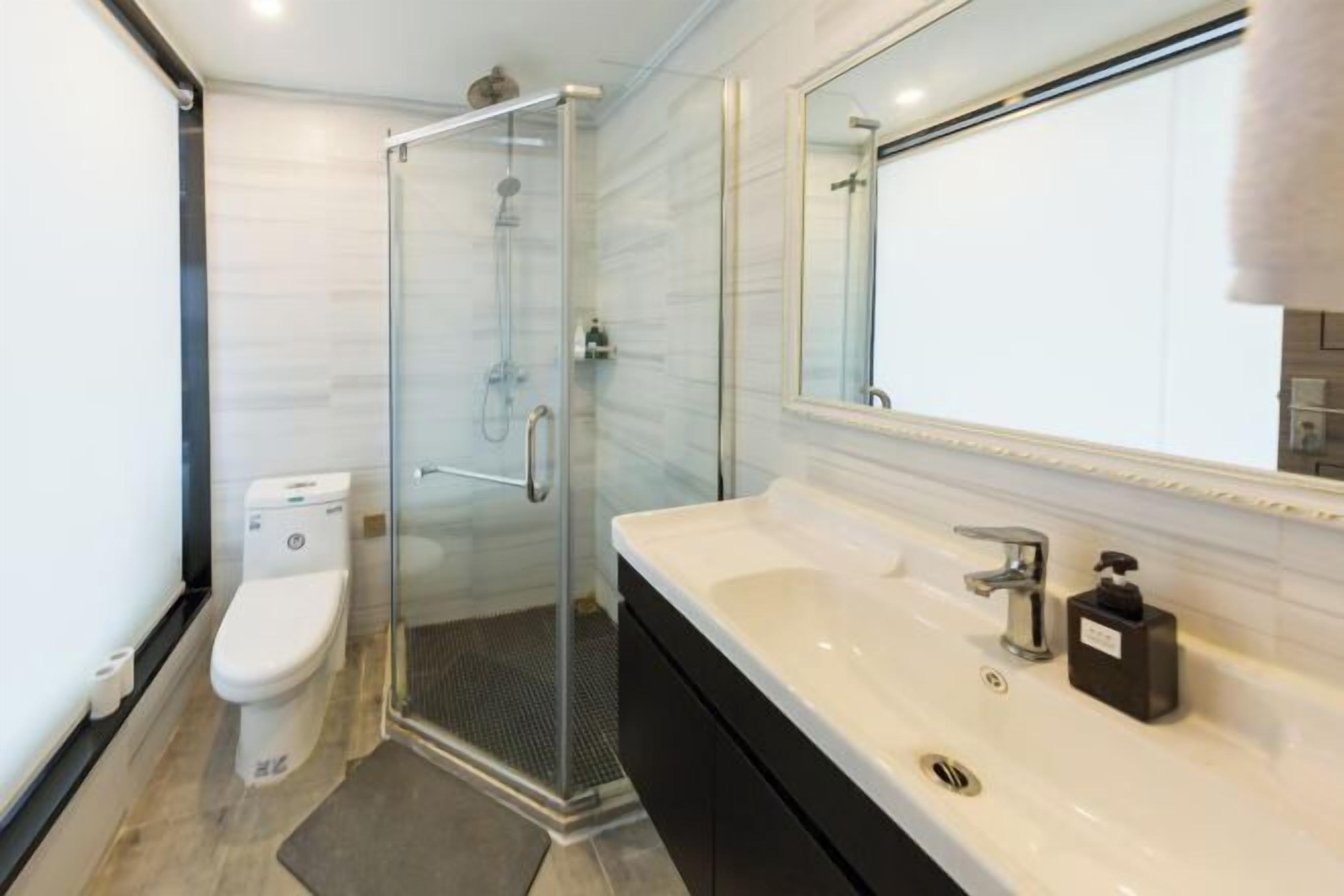 A modern bathroom with a glass-enclosed shower, a white toilet, and a vanity with a mirror.