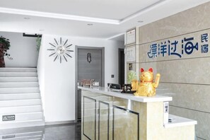 A reception area with a counter, a staircase, and a wall with a logo.