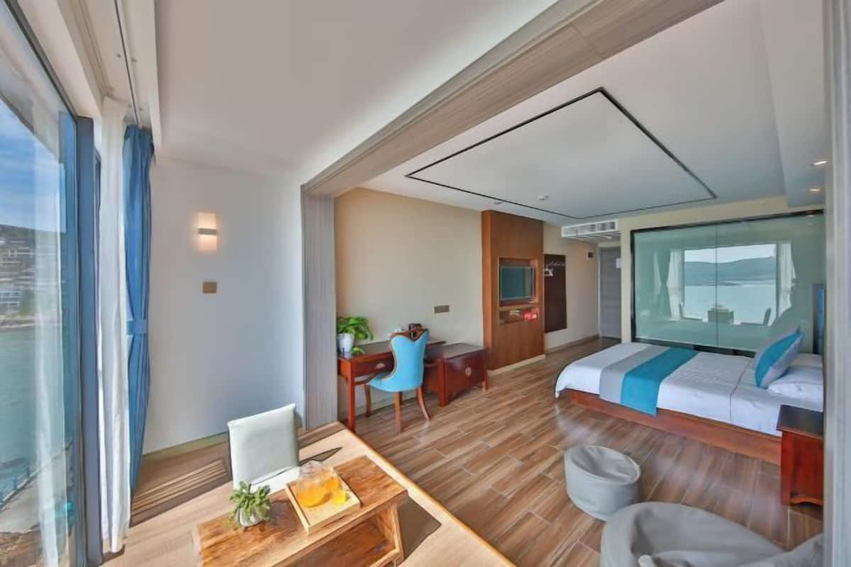 A modern hotel room with a large bed, a desk, and a seating area.