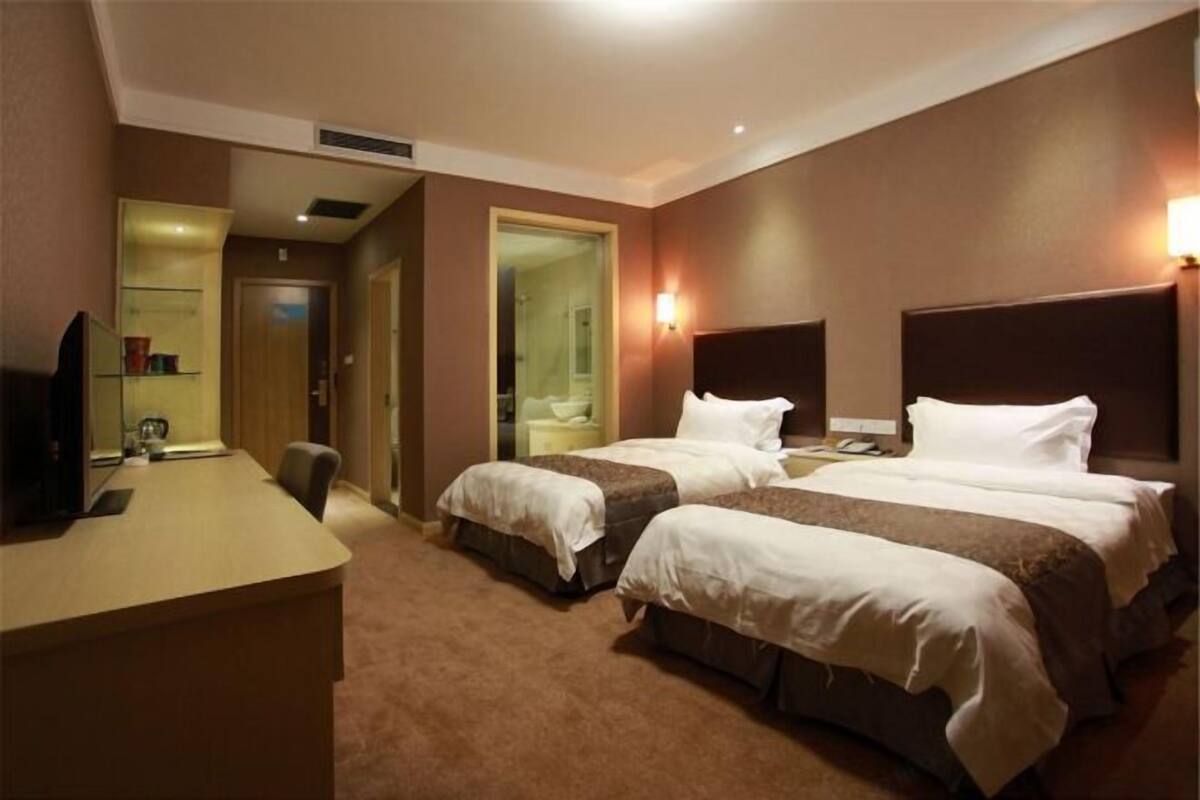 Une chambre d’hôtel avec deux lits, un bureau, une chaise et un téléviseur.