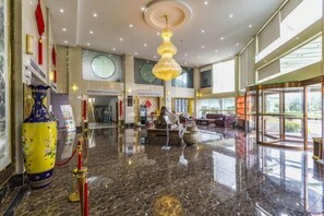Eine großzügige Lobby mit Marmorboden, einem großen Kronleuchter und einer Rezeption.