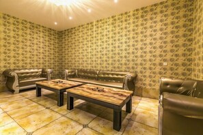 A room with a patterned wallpaper, leather sofas, and a tiled floor. - Jingya Bieyuan Hotel (Liyang)