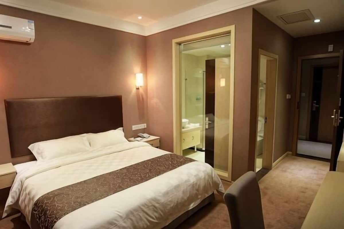 Une chambre d’hôtel avec un grand lit, une table de chevet et une porte vitrée donnant sur la salle de bain.