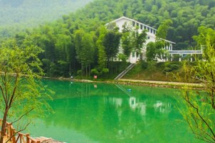 A serene lake with a house surrounded by lush greenery.