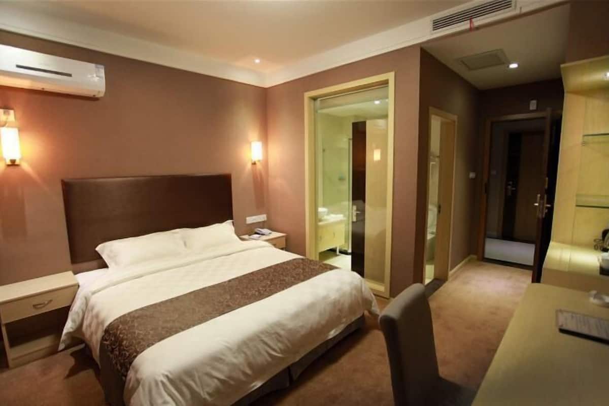 Une chambre d’hôtel avec un lit, des tables de chevet, un bureau et un miroir.