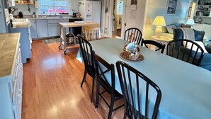 A spacious kitchen with a large island, wooden flooring, and a ceiling fan.