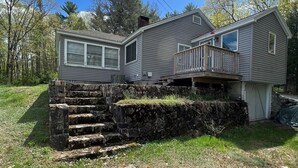 A two-story house with a stone staircase leading to a deck.