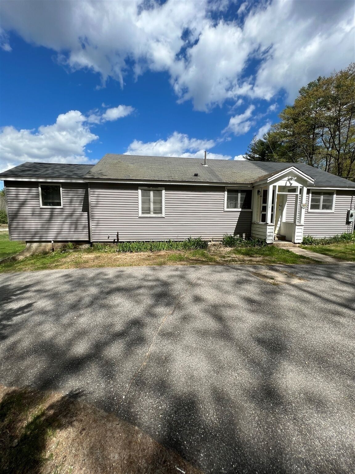 A single-story house with a grey exterior, a front porch, and a driveway leading to the entrance.