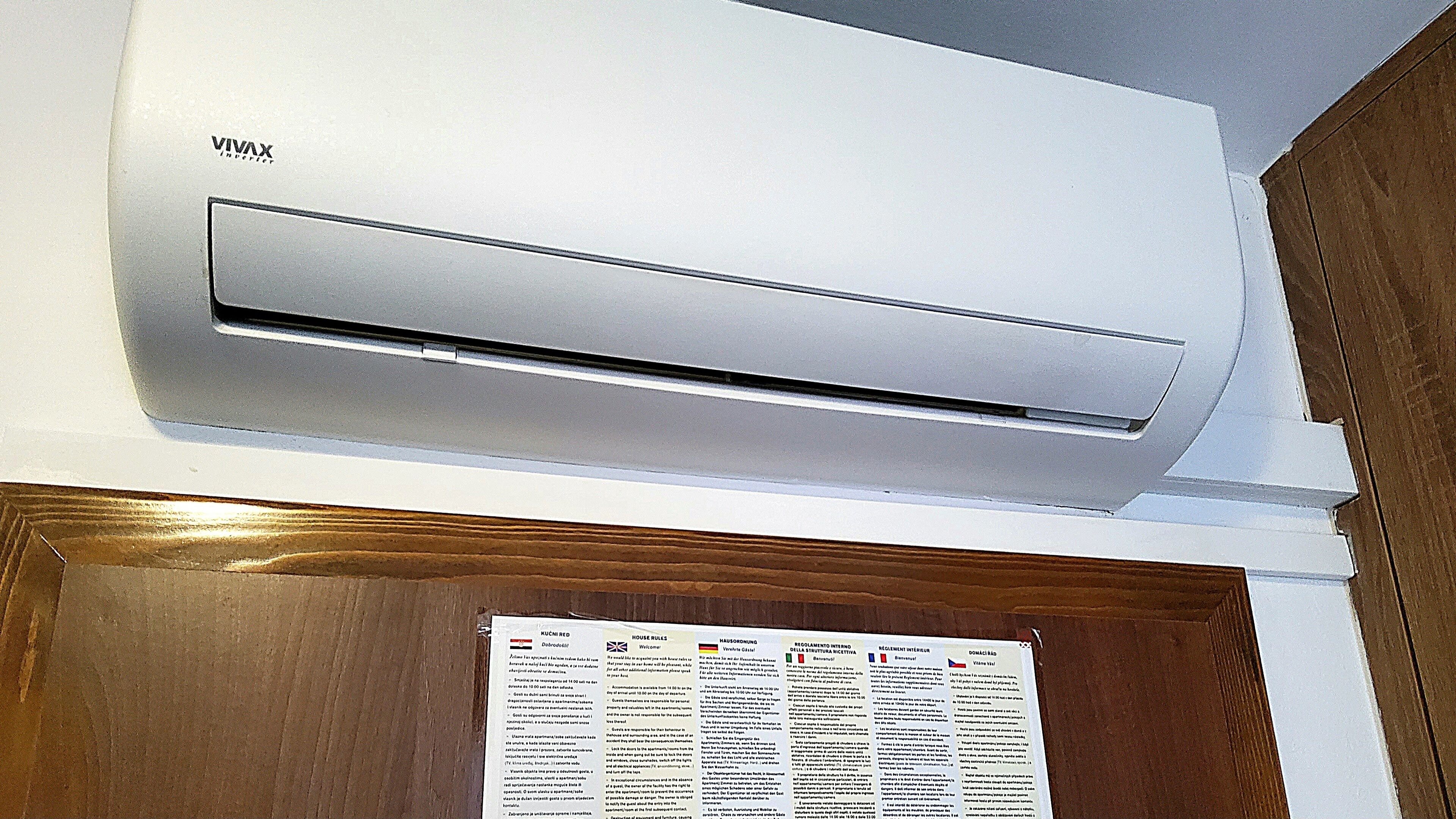 A VIVAX air conditioner mounted on a white wall above a wooden door.