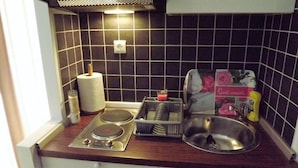Cocina compacta con estufa a gas, un lavamanos y una pequeña zona de encimera.