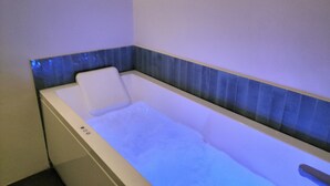 A bathtub with a blue-tiled edge, a white seat, and a control panel with buttons. - Elegant apartment with Parking, A/C, Wi-Fi, in the old town (Pistoia)