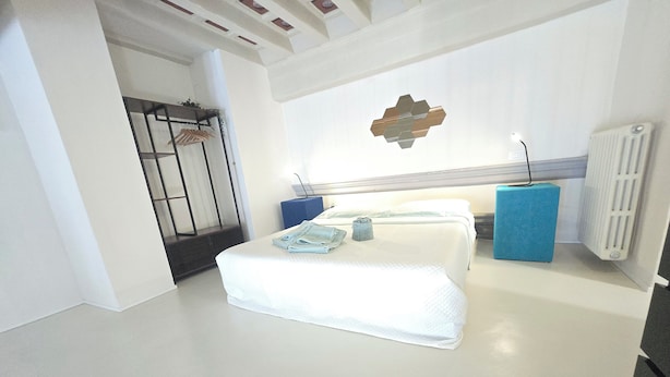 A modern hotel room with a large bed, a small desk, and a radiator. - Elegant apartment with Parking, A/C, Wi-Fi, in the old town (Pistoia)