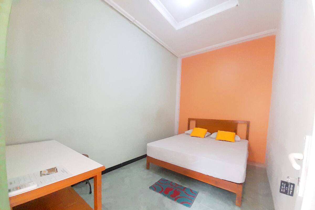 A small, compact room with a bed, a desk, and a skylight.