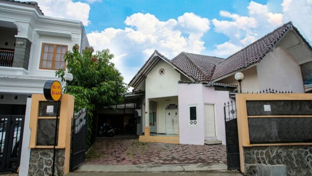 Ein Wohngebiet mit befestigter Auffahrt zu einem Haus mit Ziegeldach und kleiner Veranda.