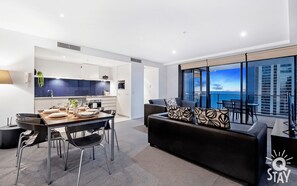 Enjoy a coastal view from the large window in this stylish living space, featuring a dining area and comfortable sofa set.