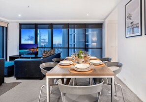 Un espace repas moderne avec vue sur la ville, un téléviseur à écran plat et une table à manger dressée pour six personnes.