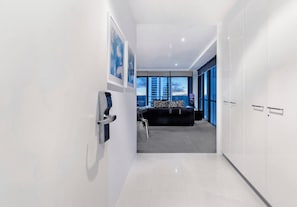 Un couloir moderne menant à une chambre avec vue sur la ville, comprenant un canapé et un bureau.