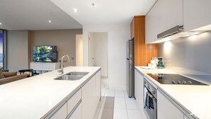 A modern kitchen with a large island, stainless steel appliances, and a view of the outdoors. - 2 Bedroom Ocean View Apartment - Q Stay (Surfers Paradise)