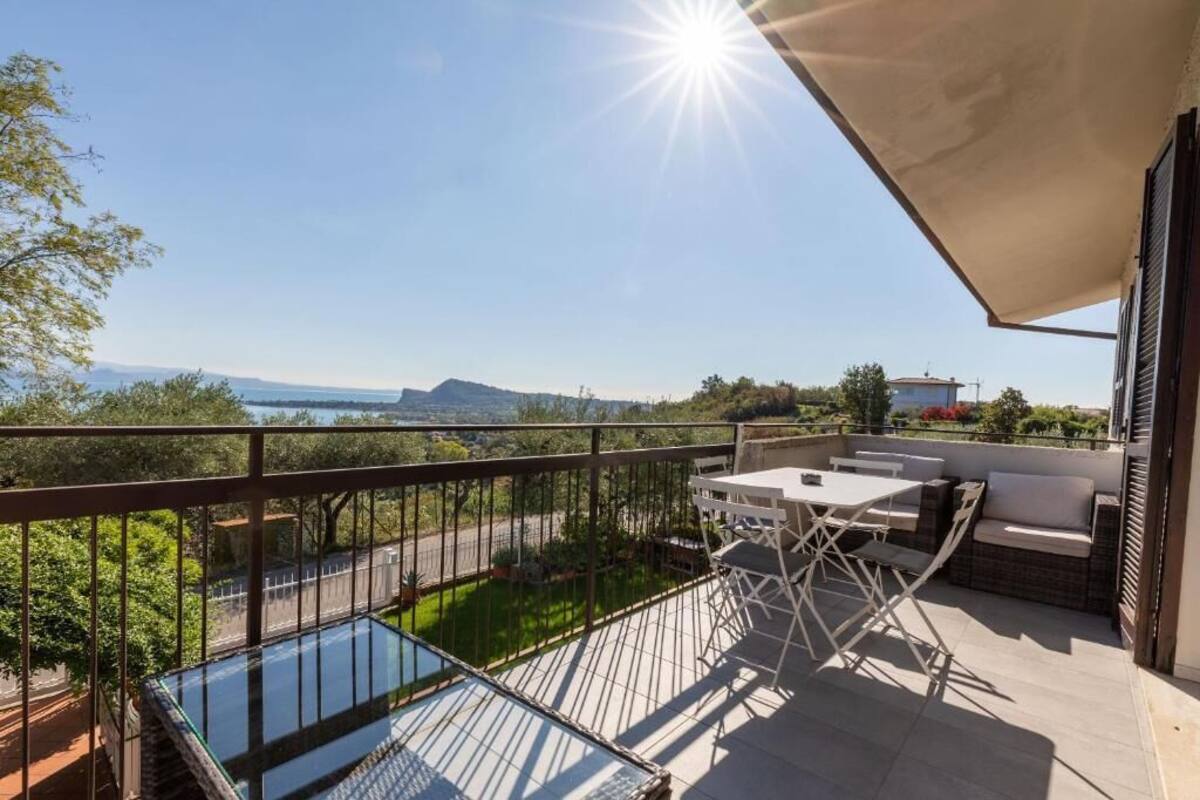 A balcony with a glass floor, outdoor furniture, and a view of the sea and mountains.
