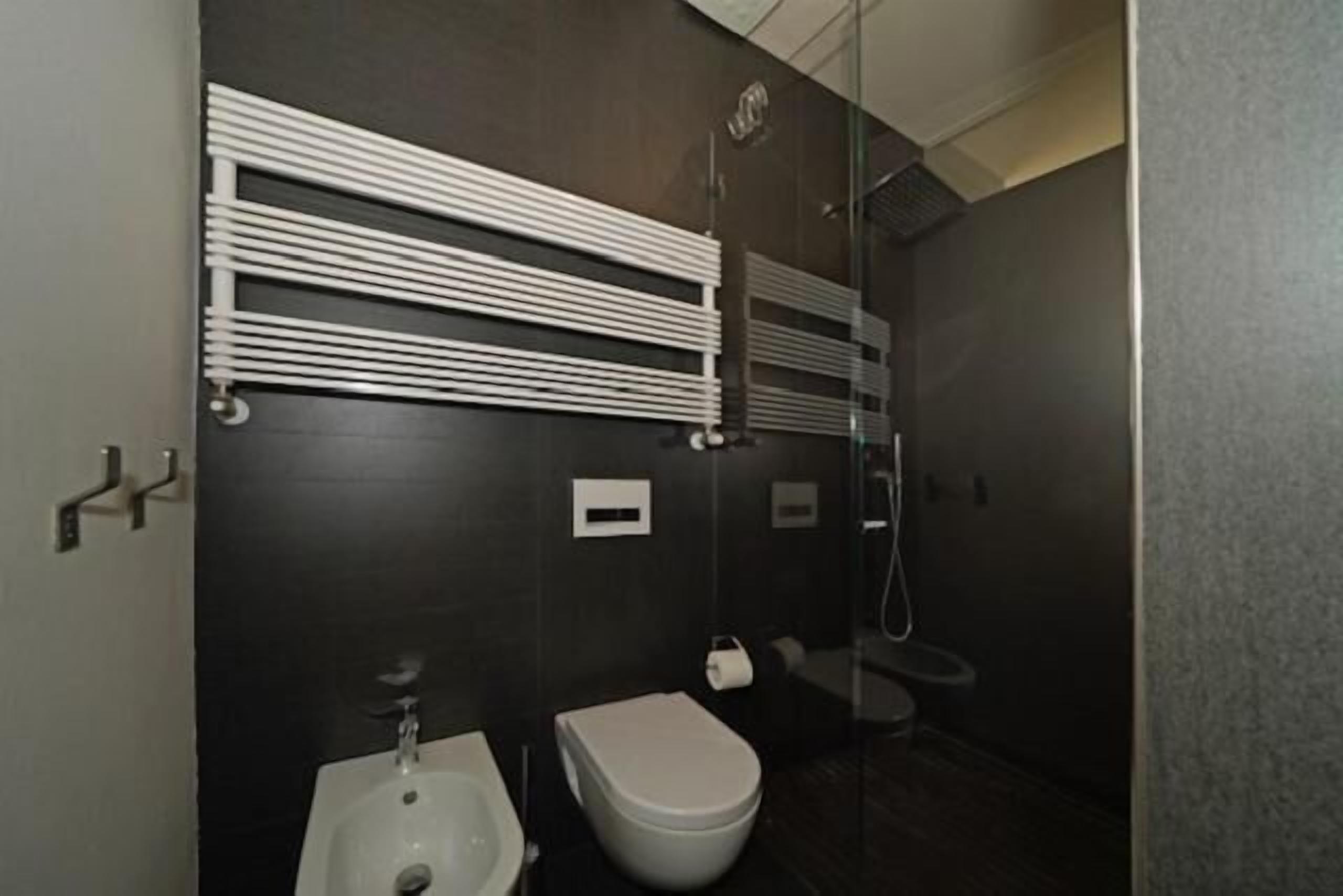 A modern bathroom with a white sink, toilet, and a glass shower enclosure.