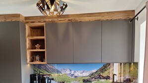 A modern kitchen with grey cabinets, a built-in oven, a coffee maker, and a decorative shelf. - Apartment with beautiful terrace to relax (Kapfing)