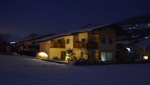 A two-story building with a balcony, snow-covered ground, and a mountain in the background. - Apartment with beautiful terrace to relax (Kapfing)