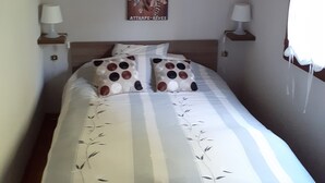 Un lit bien fait, avec une literie à rayures et des coussins décoratifs, une œuvre d’art accrochée au mur et des lampes de chevet.
