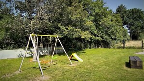 Un espace extérieur verdoyant avec une balançoire et un toboggan.