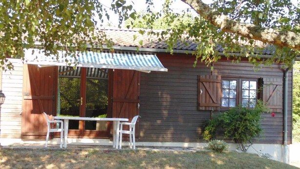 Une cabane en bois dotée d’un patio couvert, d’une table et de deux chaises.