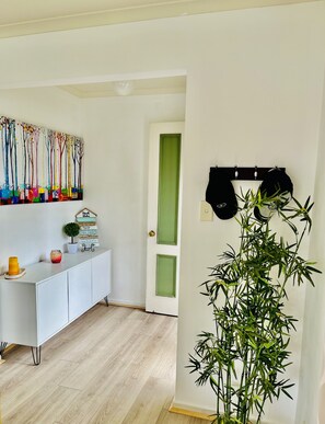 Experience a serene retreat with a vibrant abstract painting, a stylish storage cabinet, and a natural bamboo plant.