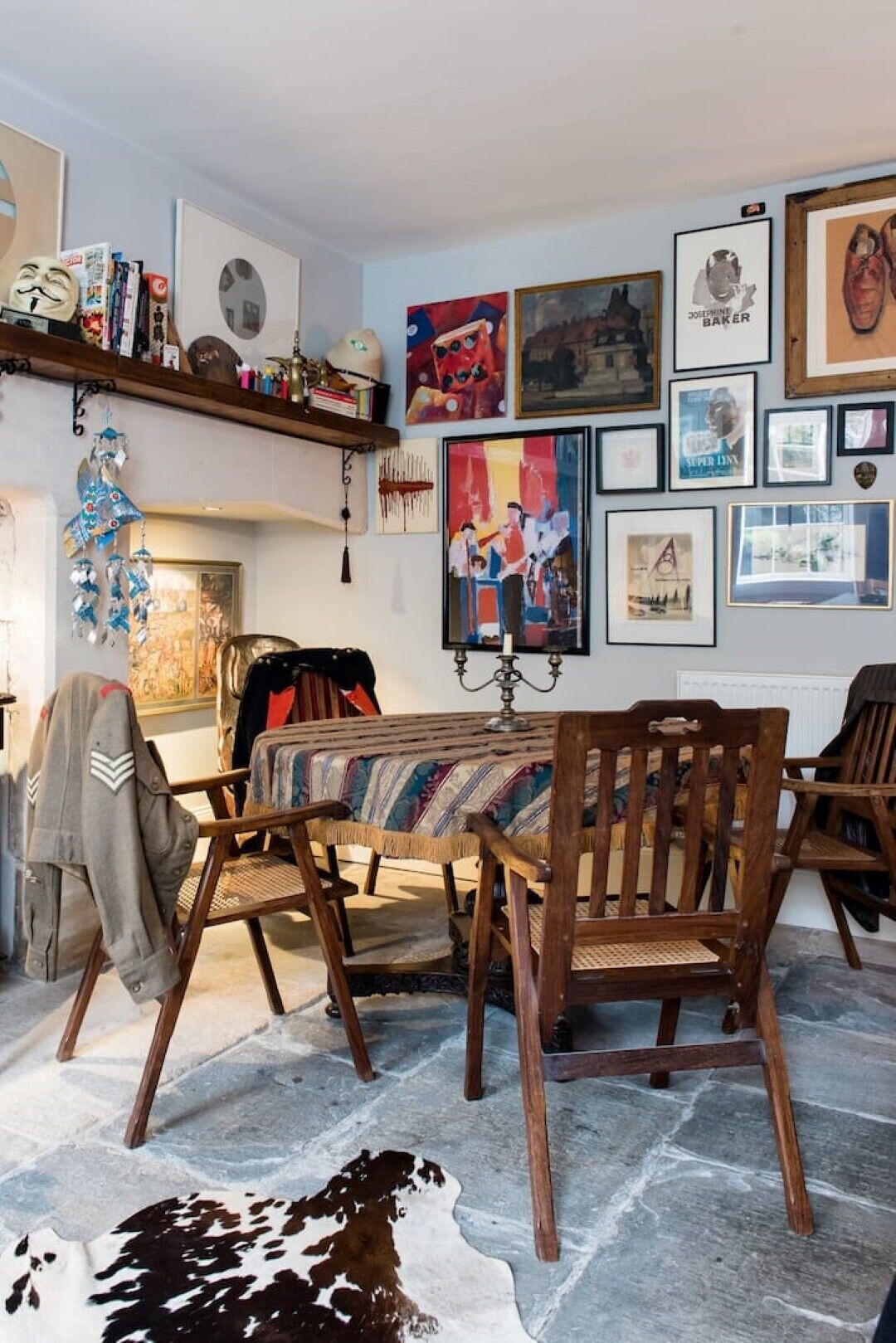 A dining area with a wooden table and chairs, surrounded by various framed artworks and decorative items.