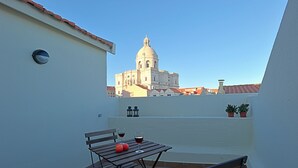 A balcony with a table, two chairs, and two potted plants. - Alfama, charming attic Terrace with river view - Lisboa vida boa 1  (Lisboa)
