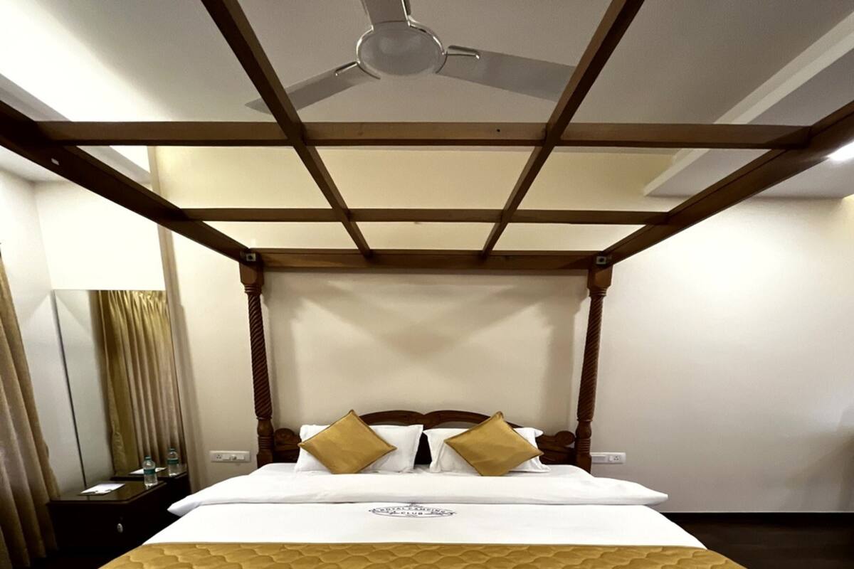 Habitación de hotel con cama con dosel, ventilador de techo y colcha de estampado geométrico.