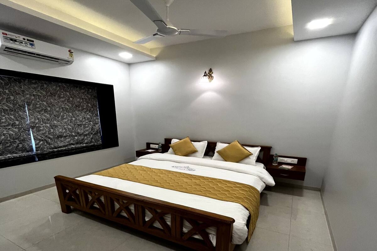 Un dormitorio moderno con cama, mesitas de noche, ventilador de techo y aire acondicionado mural.