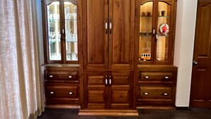 A wooden wardrobe with glass doors and multiple drawers.