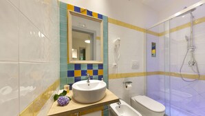 A bathroom with a sink, bidet, toilet, and shower.