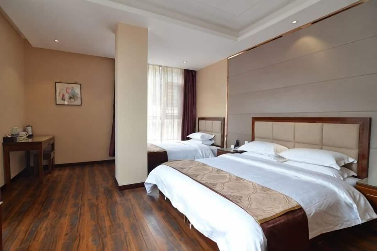 A hotel room with two beds, a desk, a chair, and a window with curtains.