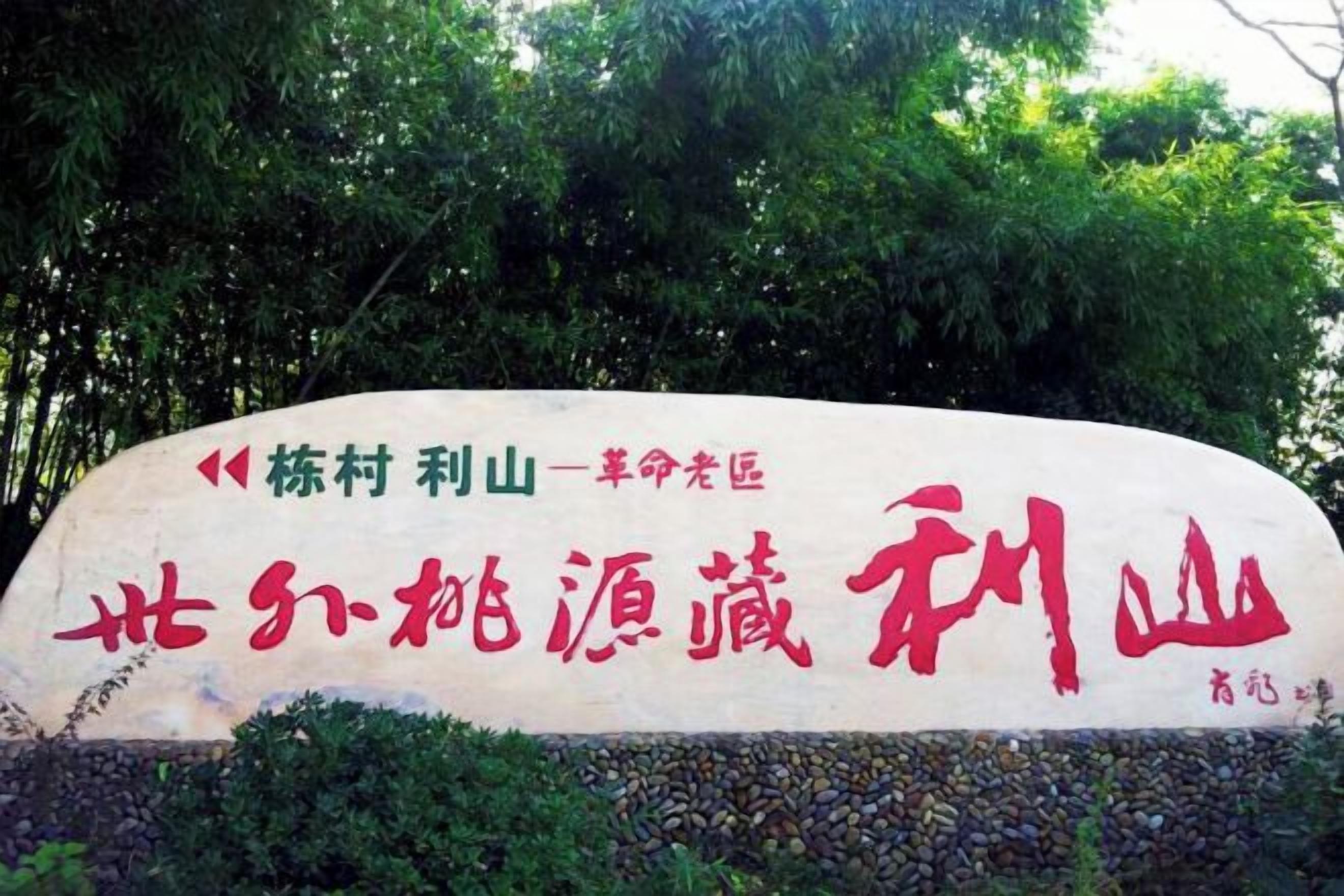 A large stone sign with Chinese characters, surrounded by greenery.