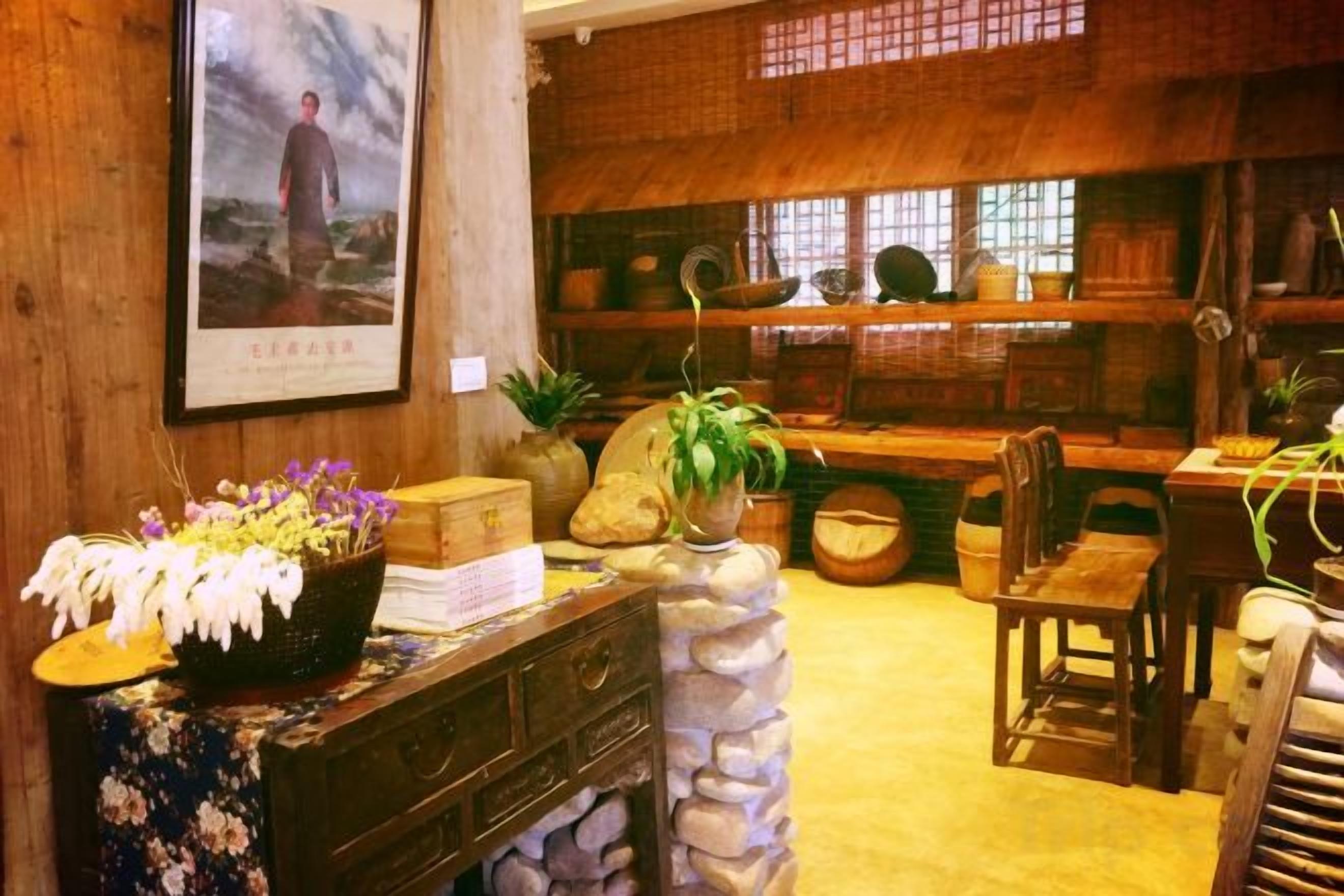 Ein traditionelles Interieur mit einem Steintisch, Holzstühlen und einem Regal mit verschiedenen Gegenständen.