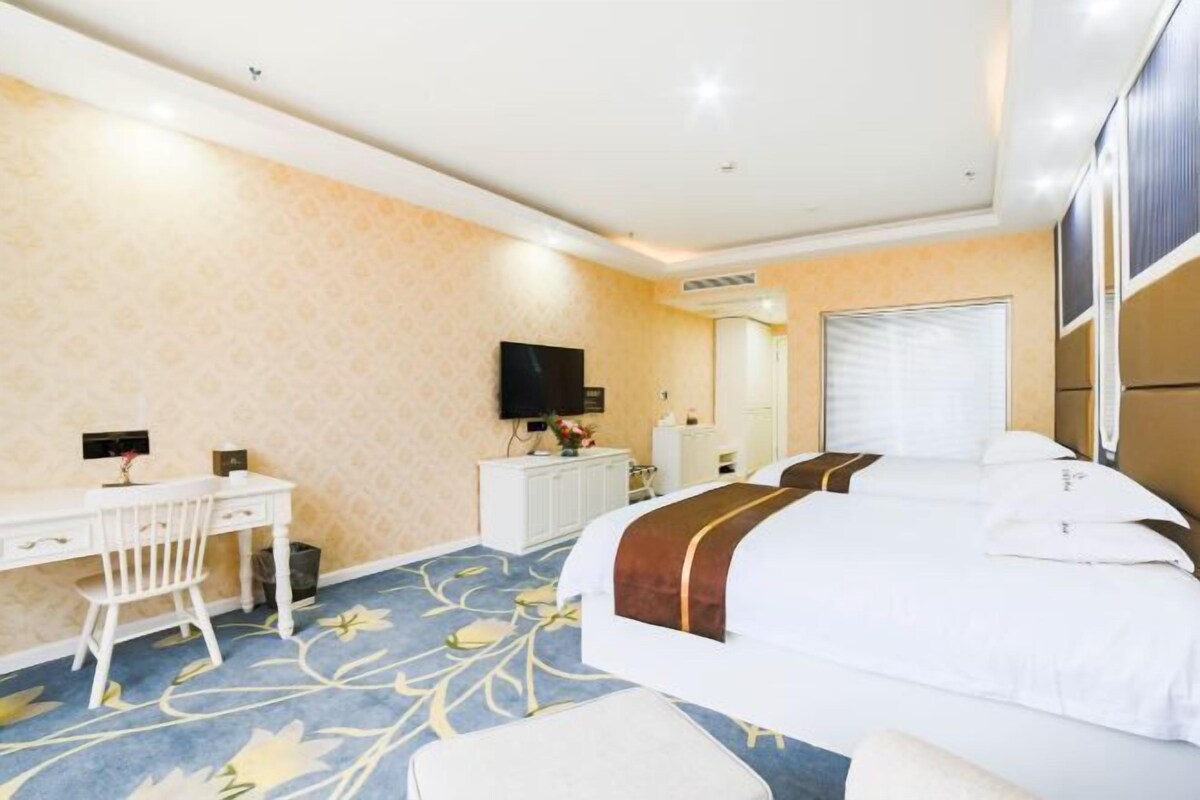 Ein Hotelzimmer mit Bett, Schreibtisch, Stuhl, Fernseher, Spiegel und Fenster.