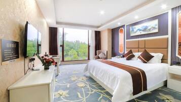 A hotel room with a large bed, a desk, a chair, and a television.
