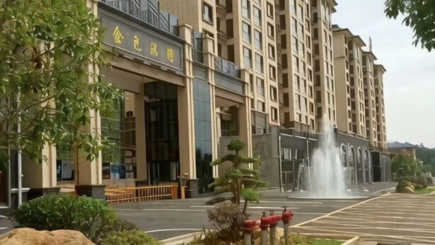 A multi-story building with a large entrance, a fountain in the center, and a parking lot with red bollards. - Nuoya Business Center Hotel (Jinggangshan City)