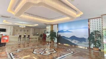 A hotel lobby with a reception desk, seating area, and a large mural of mountains.